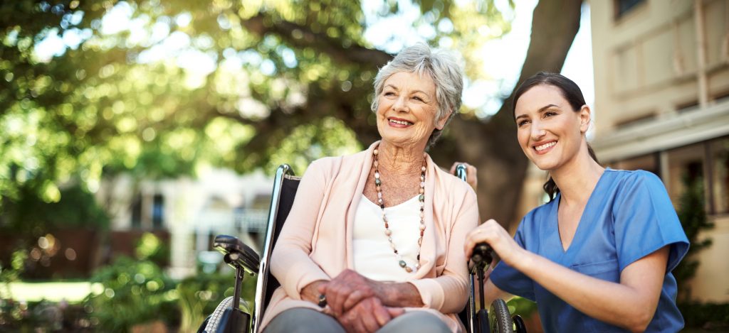 young nurse spending time with a senior woman in a wheelchair in the garden