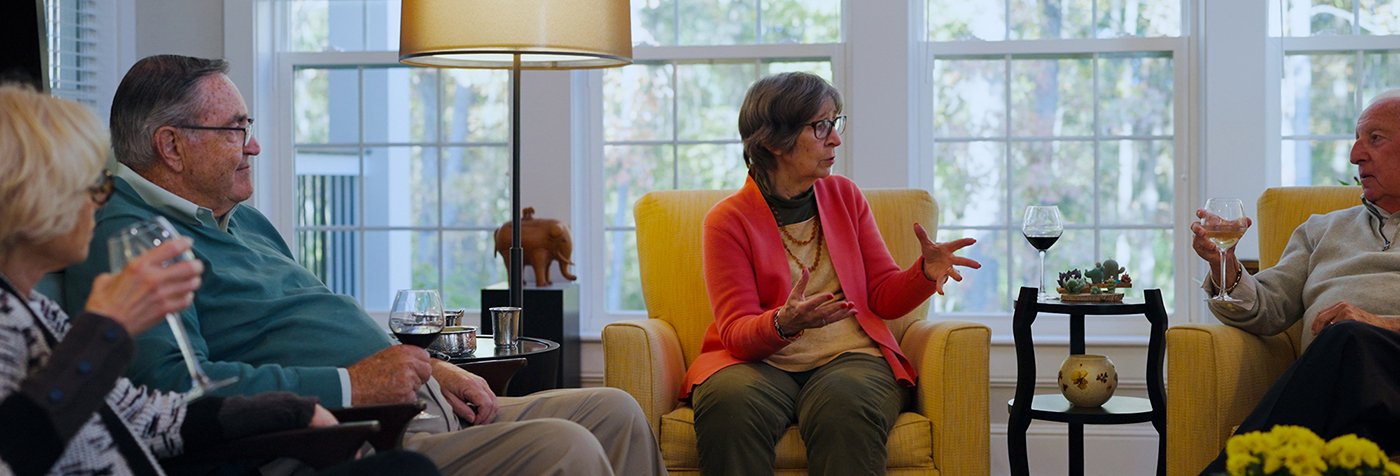 group of seniors enjoying a glass of wine together in a living area inside an apartment home