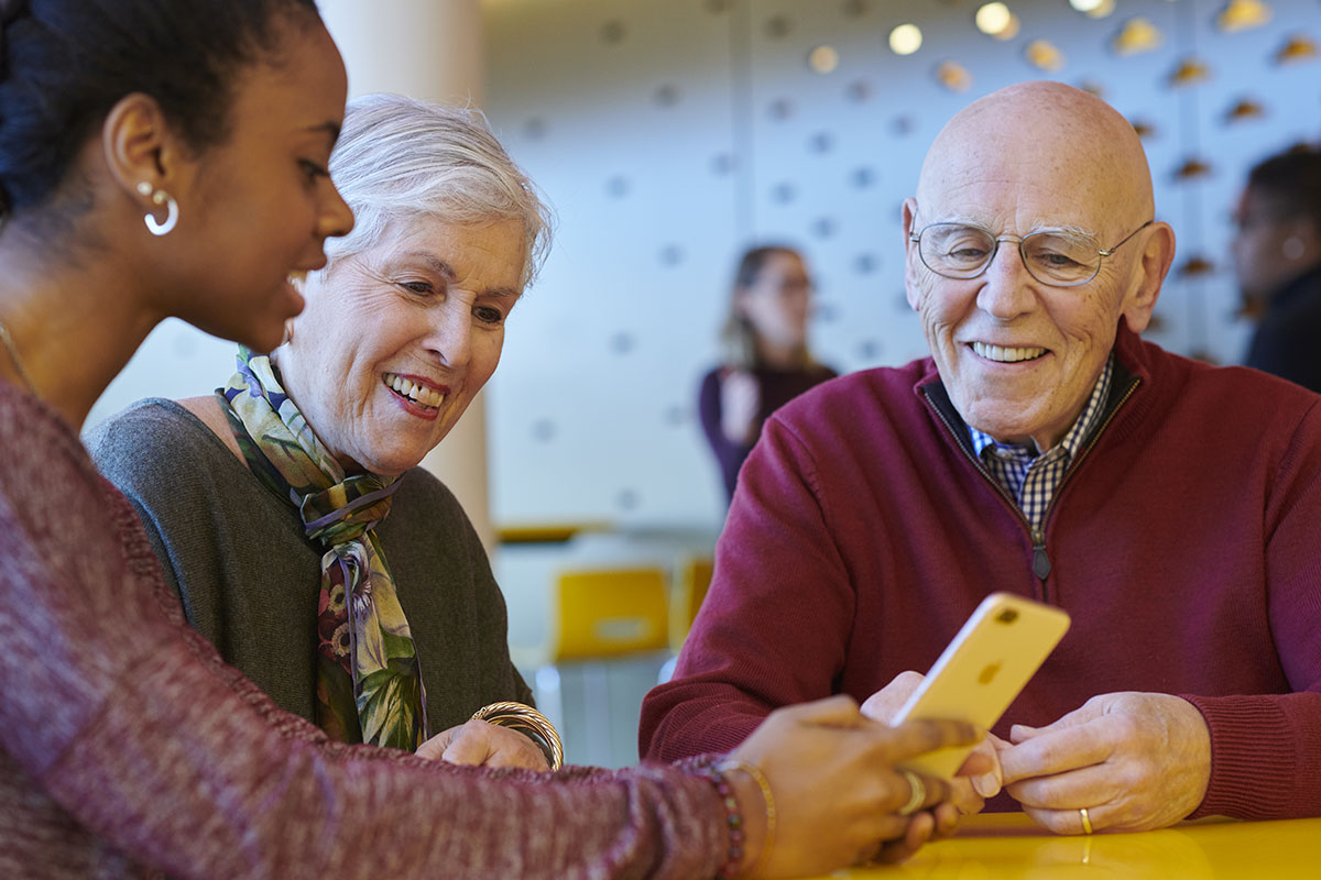 seniors participating in intergenerational learning with apple phone