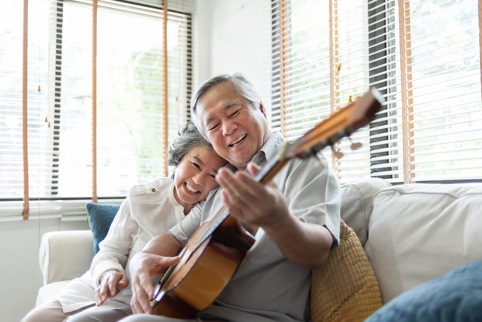 Happy senior couple listening and playing acoustic guitar together.