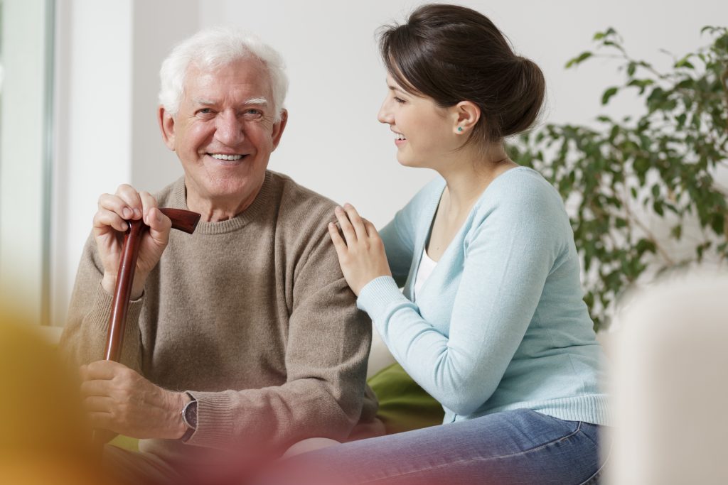 Woman embraces senior man with cane