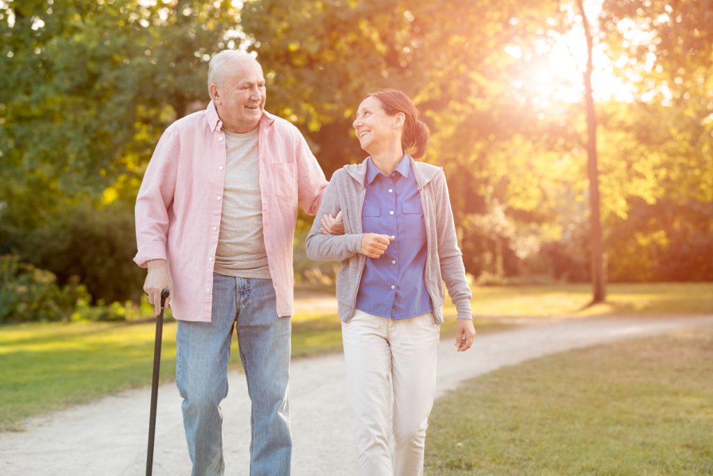 Senior man and caregiver go walking outdoors