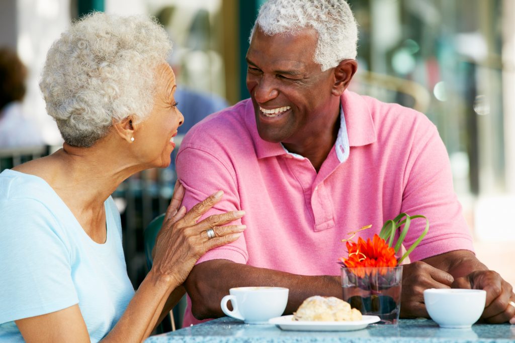 Seniors laughing while enjoying coffee in the morning