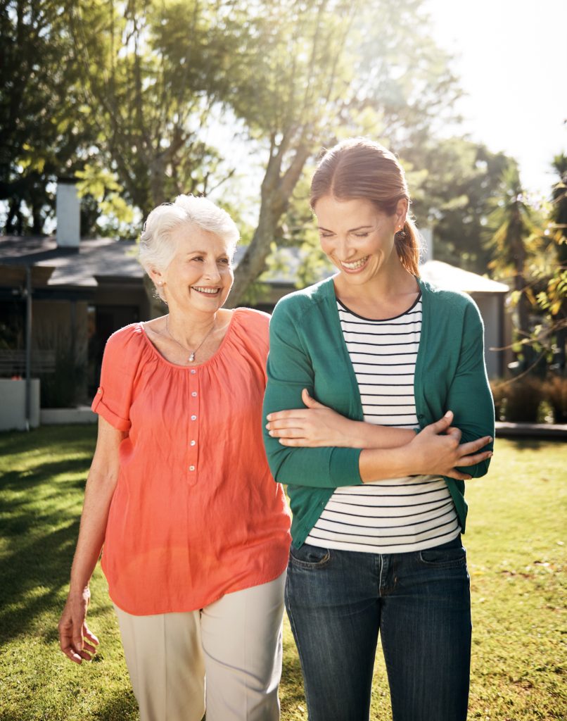 young woman going for a walk with her elderly mother in the garden