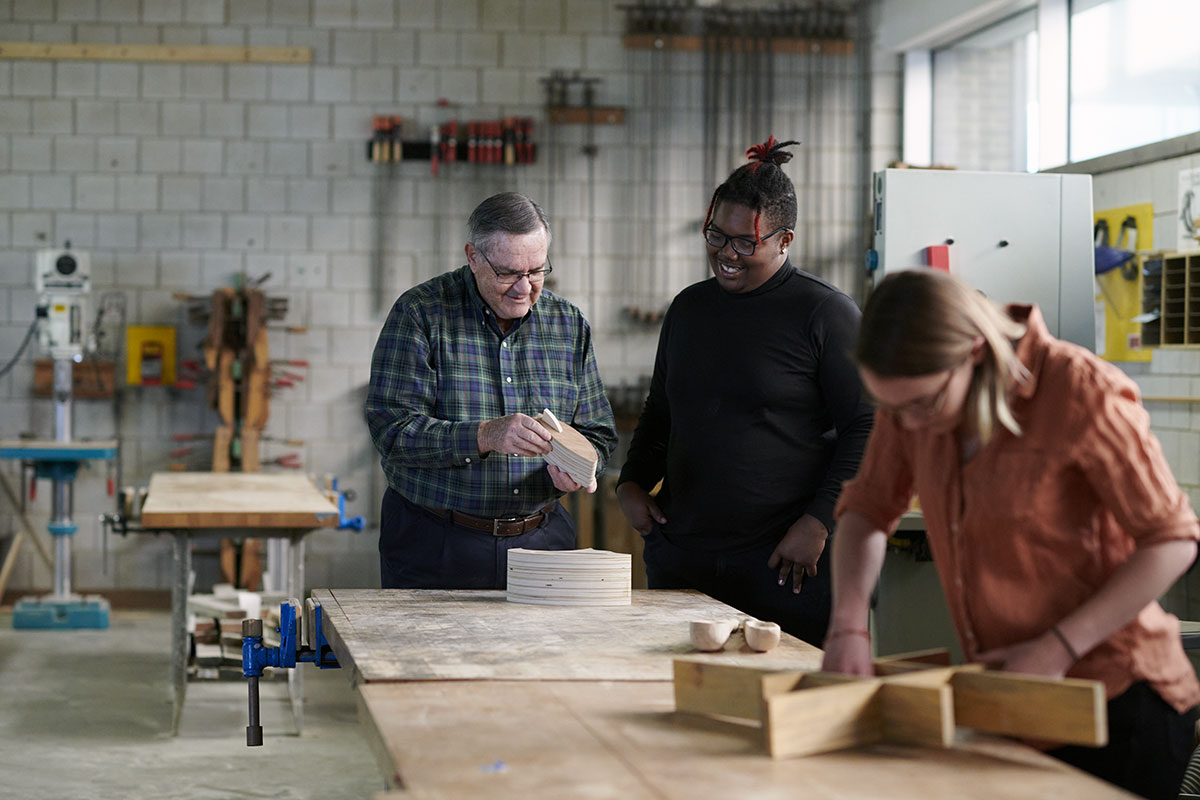 Senior teaching a student about woodshop project