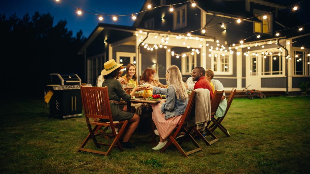 Multigenerational dinner outside under strings of lights